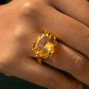 Op de afbeelding: Een gouden ring met een grote, ovale, gele topaas edelsteen.