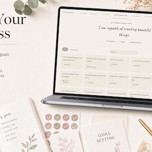 Pu&ograve; includere: Un laptop mostra un'app per la definizione degli obiettivi con affermazioni. L'immagine include un taccuino, adesivi e biglietti con testo come "Goal Setting" e "Track Your Progress". La tavolozza dei colori &egrave; tenue, con accenti beige, rosa e oro.
