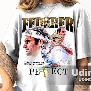 May include: White t-shirt with a vintage-style graphic of tennis player Roger Federer. The graphic includes a quote from Federer: "I fear no one but respect everyone." The text "PERFECT" is below the graphic, with a stylized "R" in gold. The shirt also features the text "Federer" in gold letters.