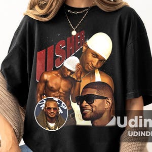 Può includere: Maglietta nera con una grafica vintage di Usher, con tre diverse immagini del cantante. Il testo "Usher" è stampato in rosso e bianco sulla maglietta.