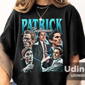 Puede incluir: Camiseta negra con un estampado gráfico de Patrick Bateman de la película American Psycho. El gráfico es un collage de diferentes imágenes de Patrick Bateman, incluyendo un primer plano de su rostro, una foto de él con traje y una foto de él con una pistola. El texto "Patrick Bateman" está impreso en azul sobre el gráfico.