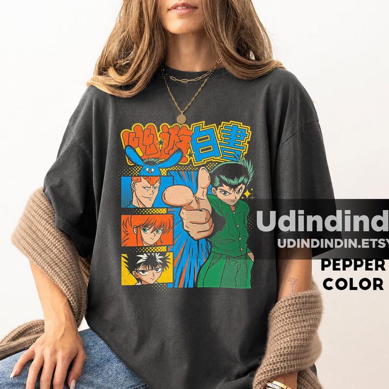 Puede incluir: Una camiseta de manga corta gris carb&oacute;n con un estampado gr&aacute;fico de personajes de anime de YuYu Hakusho. El dise&ntilde;o incluye una figura central se&ntilde;alando hacia adelante, rodeada de retratos de personajes m&aacute;s peque&ntilde;os en marcos naranjas y azules.