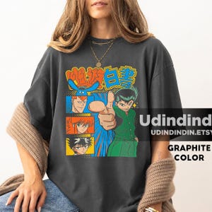 Puede incluir: Una camiseta de manga corta color grafito con un estampado gr&aacute;fico de personajes de anime de YuYu Hakusho. El dise&ntilde;o incluye un personaje central se&ntilde;alando hacia adelante, rodeado de paneles m&aacute;s peque&ntilde;os con otros personajes y texto japon&eacute;s.
