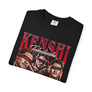 K&ouml;nnte beinhalten: Schwarzes T-Shirt mit einem roten Grafikdesign mit der Aufschrift "KENSHI" und "Takahashi". Das Design zeigt drei M&auml;nner mit Augenbinden. Das T-Shirt hat einen Rundhalsausschnitt und ein Etikett.