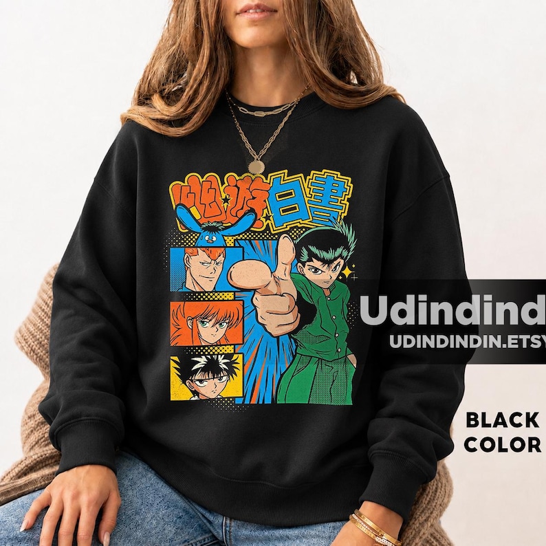 May include: A black sweatshirt featuring a colorful graphic print of anime characters from YuYu Hakusho. The design includes a central character pointing forward, surrounded by smaller panels of other characters and Japanese text in orange and blue.