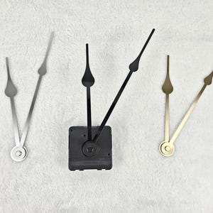 Könnte beinhalten: Uhrzeiger in Silber, Schwarz und Gold. Das Set enthält ein schwarzes Uhrwerk und verschiedene Stile von Stunden- und Minutenzeigern. Die Zeiger sind aus Metall und für DIY-Uhrenprojekte konzipiert.