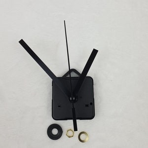 Könnte beinhalten: Schwarzes Uhrwerk mit drei Zeigern, einem quadratischen Gehäuse und Montagematerial. Die Zeiger sind lang und rechteckig. Der Mechanismus ist für DIY-Uhrenprojekte konzipiert. Die Zeiger sind schwarz, das Gehäuse quadratisch.