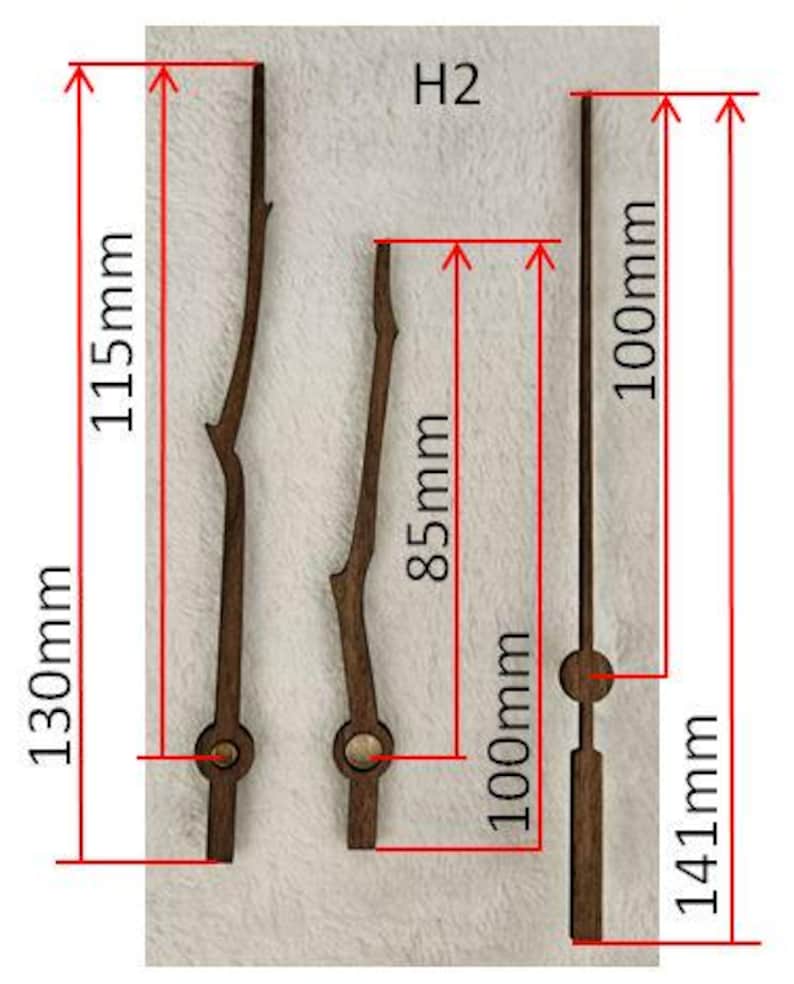 May include: Three wooden clock hands in varying styles. The longest hand is 130mm long, the second is 85mm, and the third is 141mm. The hands are dark brown and have a natural, twig-like design. The image includes measurements in millimeters.