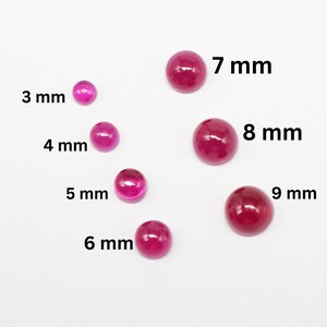 Op de afbeelding: Een verzameling gepolijste, ronde, robijnrode edelstenen in verschillende maten, variërend van 3 mm tot 9 mm in diameter. De maten staan duidelijk naast elke steen, wat een visuele gids biedt voor de verschillende afmetingen.