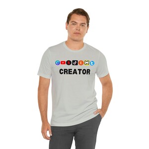 May include: A light gray t-shirt with the text "CONTENT CREATOR" printed in black. The text is surrounded by colorful social media icons, including Facebook, YouTube, Instagram, TikTok, Twitter, and Snapchat.