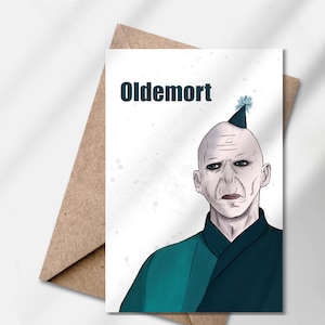 Op de afbeelding: Wenskaart met een cartoon illustratie van een kale karakter, het woord "Oldemort" boven het hoofd van het karakter. Het karakter draagt een feesthoed en een teal en zwarte outfit. De kaart wordt gecombineerd met een bruine envelop.