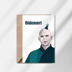Op de afbeelding: Wenskaart met een digitale illustratie van een personage, de tekst "Oldemort" bovenaan. Het personage heeft een kale kop, een bleke huid en een feesthoed. De kaart wordt gepresenteerd met een bruine envelop.