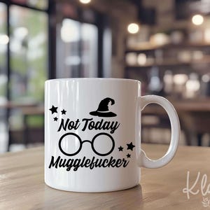 May include: A white ceramic mug featuring black graphic elements including a pointed hat, round glasses, and small stars. The text printed on the front reads Not Today Mugglefucker in a stylized black font. The mug has a standard handle.