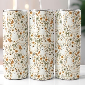 May include: Three cylindrical tumblers with a white straw each, featuring a repeating pattern of white ghosts, cream-coloured pumpkins, sage green bows, and small orange and brown autumn flowers on a light cream background with brown foliage.