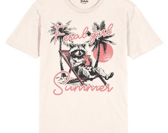 May include: A beige t-shirt with a graphic of a raccoon sitting in a beach chair with a drink, palm trees, and the text "Feral girl summer" in pink.