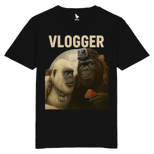Puede incluir: Camiseta negra con una ilustraci&oacute;n humor&iacute;stica de dos gorilas. Uno lleva una c&aacute;mara GoPro y sostiene una seta. La palabra "VLOGGER" est&aacute; impresa encima de los gorilas. El otro gorila tiene una etiqueta con el nombre "FRED".