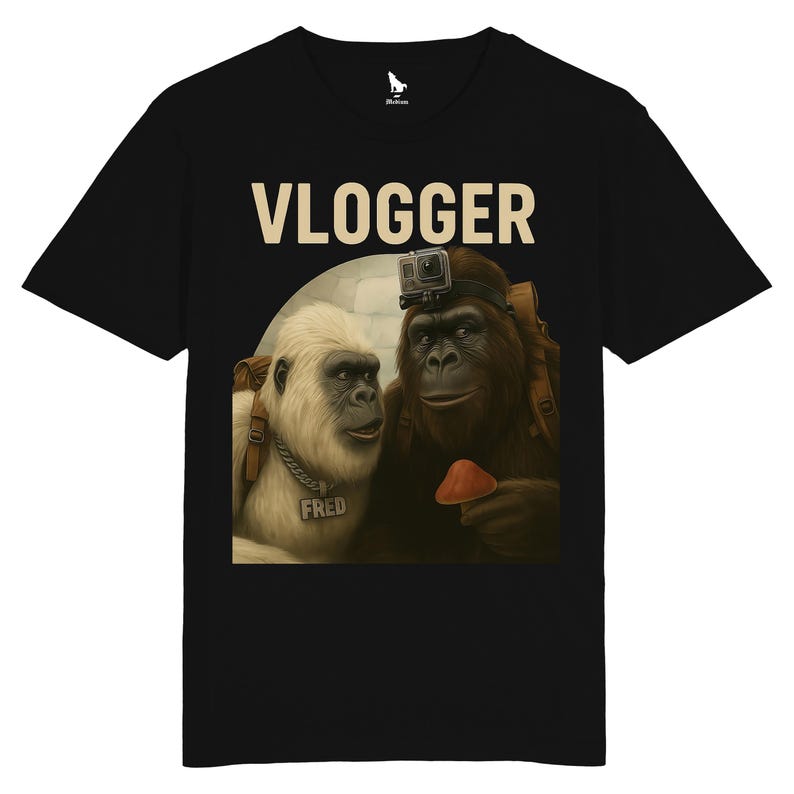 Puede incluir: Camiseta negra con una ilustraci&oacute;n humor&iacute;stica de dos gorilas. Uno lleva una c&aacute;mara GoPro y sostiene una seta. La palabra "VLOGGER" est&aacute; impresa encima de los gorilas. El otro gorila tiene una etiqueta con el nombre "FRED".