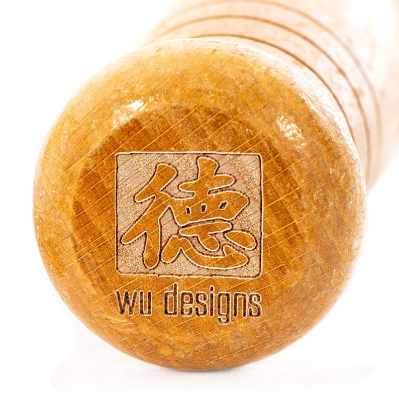 K&ouml;nnte beinhalten: Nahaufnahme eines Nudelholzes aus Holz mit einem quadratischen Design mit chinesischen Schriftzeichen und dem Text "wu designs".