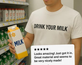 May include: A white t-shirt with the text "DRINK YOUR MILK" printed in black. A person is holding a carton of milk with a yellow background and a white flower design. The carton says "MILK" in black text. The image includes a five-star review that says "Looks amazing! Just got it in. Great material and seems to be very nicely made!" and "Verified Etsy Buyer."