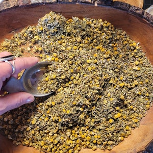 May include: A wooden bowl filled with dried herbs and flowers, including chamomile, lavender, and other botanicals. The bowl is made from a tree trunk and has a natural, rustic look.