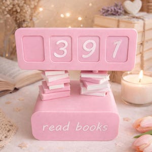 May include: A pink book counter with the numbers 391 displayed. The counter is supported by stacks of miniature books. The base of the counter reads "read books". The image has a soft, romantic aesthetic.