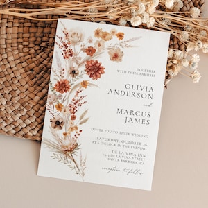 Könnte beinhalten: Eine Hochzeitseinladung mit einem floralen Design in Orange-, Braun- und Weißtönen. Die Einladung enthält die Namen Olivia Anderson und Marcus James, das Datum Samstag, den 26. Oktober, und den Veranstaltungsort De La Vina Inn, 1323 De La Vina Street, Santa Barbara, CA. Der Text "Empfang folgt" befindet sich am unteren Rand der Einladung.