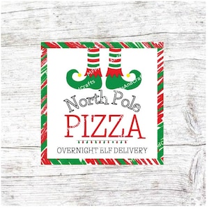 May include: A white square sign with red and green striped borders. The sign says "North Pole Pizza" with elf shoes at the top and the text "Overnight Elf Delivery" at the bottom.