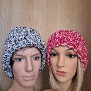 Puede incluir: Dos gorros de punto, uno blanco y negro y otro rosa y blanco, en cabezas de maniquí.