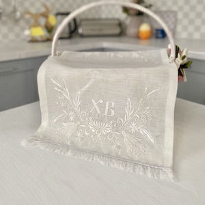 May include: White linen Easter basket liner with embroidered floral design and the letters "XB" in the center.
