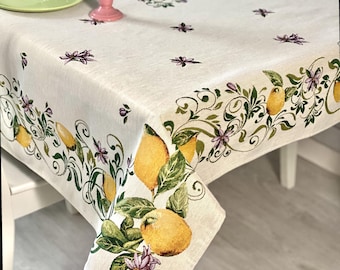 May include: A white linen tablecloth with a lemon and floral design. The tablecloth has a border of lemons, leaves, and flowers in shades of green, yellow, and purple.