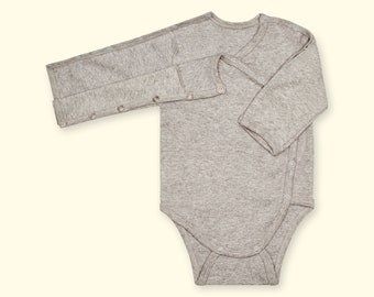 May include: A light gray baby bodysuit with long sleeves. The bodysuit has a wrap-style design with snap closures along the side and at the crotch. The fabric appears to be a soft, knit material.