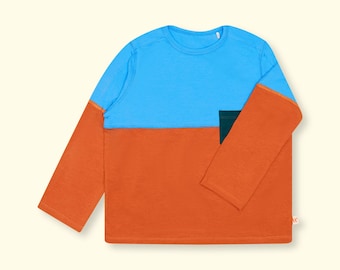 May include: A long-sleeved shirt with a color block design. The top half of the shirt is light blue, the bottom half is orange, and there is a small green square on the right side of the shirt.