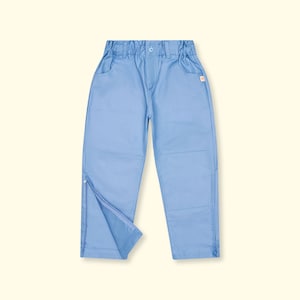 Könnte beinhalten: Hellblaue Hose mit elastischem Bund und Knopfverschluss. Die Hose hat zwei Vordertaschen und Reißverschlüsse an den Knöcheln. Ein kleines orangefarbenes Etikett ist auf der rechten Seite sichtbar. Die Hose ist aus strapazierfähigem Stoff gefertigt.