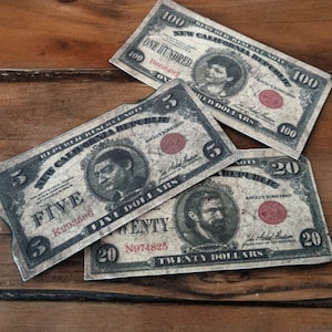 K&ouml;nnte beinhalten: Vier Banknoten im Vintage-Stil mit roten Siegeln und Portr&auml;ts von Personen. Die Scheine sind im Wert von f&uuml;nf, zwanzig und hundert Euro. Die Scheine liegen auf einer Holzoberfl&auml;che.