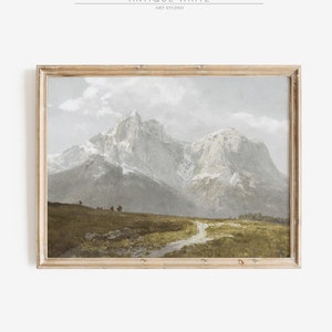 May include: A framed painting depicting a mountain range with snow-capped peaks. The mountains are painted in shades of grey and white, with a green valley in the foreground. The painting is framed in a light wood frame.