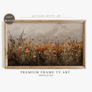 May include: A framed landscape painting depicting a field of wildflowers in orange, yellow, and brown hues. The artwork is labelled "Antique White Art" and "Premium Frame TV Art". The frame is made of light-coloured wood.