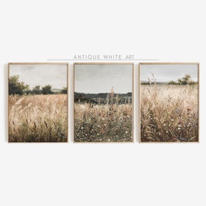 May include: Three framed landscape paintings depicting a field of tall grass and wildflowers in shades of green, brown, and white. The paintings are set against a pale blue sky.
