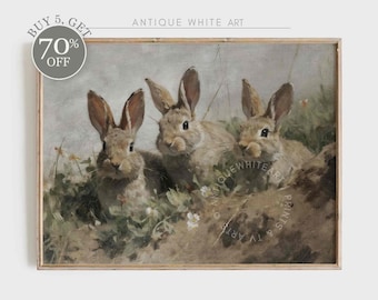 Puede incluir: Una pintura vintage de tres conejos marrones sentados en un campo de follaje verde y flores blancas. Los conejos miran al espectador. La pintura está enmarcada en un marco de madera marrón claro.