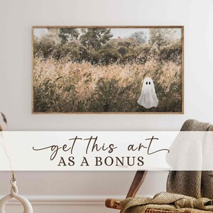 May include: A framed artwork featuring a field scene with a white ghost figure. The artwork has a natural color palette with a ghost in the center. The text "get this art AS A BONUS" is displayed on a white banner below the artwork.