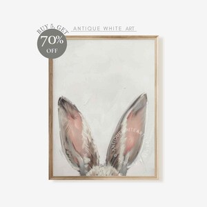 May include: A close-up of a painting of a rabbit's ears. The ears are painted in shades of gray and pink, and the background is a light gray. The painting is framed in a light wood frame.