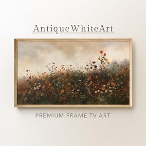 Puede incluir: Un cuadro de paisaje rectangular enmarcado que muestra un campo de flores silvestres en tonos naranja, rojo y blanco sobre un cielo nublado y apagado. El texto Antique White Art y PREMIUM FRAME TV ART aparece impreso sobre y bajo la obra.
