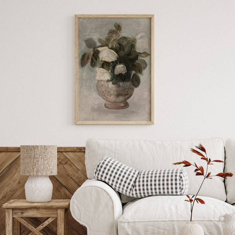 May include: A framed painting of a bouquet of white flowers in a pink vase. The flowers are arranged in a vase with a decorative pattern. The painting is set against a light blue background.