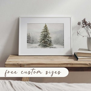 May include: A framed art print depicting a winter scene with a snow-covered fir tree in a snowy forest. The artwork is in a white frame and is displayed on a wooden surface. The text "free custom sizes" is at the bottom of the image.