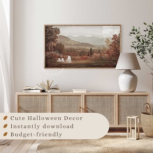 May include: A rectangular wall art print featuring a landscape painting of a valley with mountains in the background and three white ghost figures in the foreground. The print is displayed in a wooden frame on a wall above a light wood cabinet.
