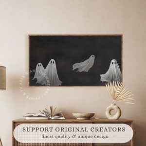 May include: Three white ghosts with black eyes float against a dark background. The ghosts are in a framed print with a wooden frame.