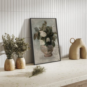 May include: A framed painting of a bouquet of white flowers in a pink vase, with a light blue background. The painting is leaning against a white tiled wall.