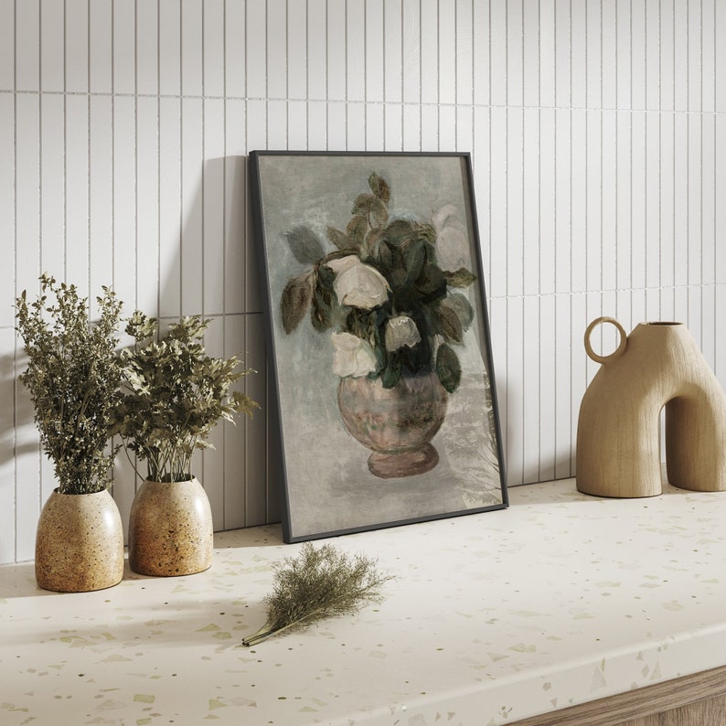 May include: A framed painting of a bouquet of white flowers in a pink vase, with a light blue background. The painting is leaning against a white tiled wall.