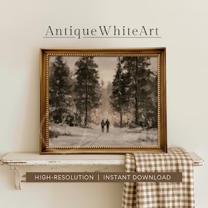 Op de afbeelding: Een ingelijste kunstdruk met een monochrome landschapsschildering van twee figuren die door een besneeuwd bos met hoge dennenbomen lopen. Het kunstwerk zit in een goudkleurige lijst met een kralenrand. De tekst AntiqueWhiteArt staat boven de lijst en de tekst HIGH-RESOLUTION | INSTANT DOWNLOAD is eronder zichtbaar.