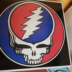 May include: A black and white Grateful Dead Steal Your Face logo with a red and blue background. The logo is a skull with a lightning bolt in the forehead.