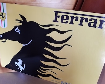 Puede incluir: Un letrero amarillo con la palabra "Ferrari" en letras negras. Una silueta negra de una cabeza de caballo con una melena fluida está en el lado izquierdo del letrero. Una silueta blanca más pequeña de un caballo encabritado está en la esquina inferior izquierda del letrero.